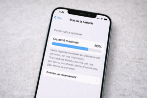 Batterie iPhone : quand faut-il la changer ? iPhone affichant l’état de santé de la batterie avec indicateur de capacité maximale sur un fond neutre.